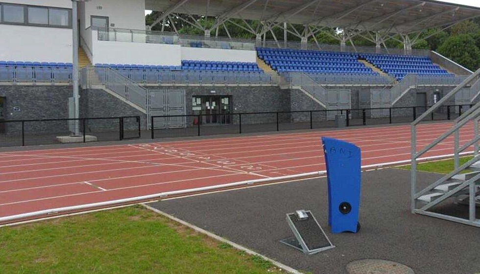 A flip-lid in-ground service unit installed at an athletics stadium, providing power and water supplies when required to assist with maintaining the ground and powering equipment during events.